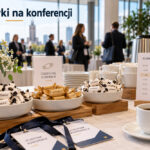 Ilustracja AI: krówki w niewielkich misach na konferencyjnym stole kawowym, obok planu wydarzenia.
